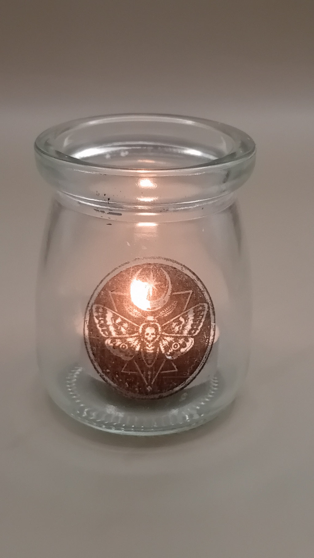 Engraved gothic glass votive candle holder lit with a tea light