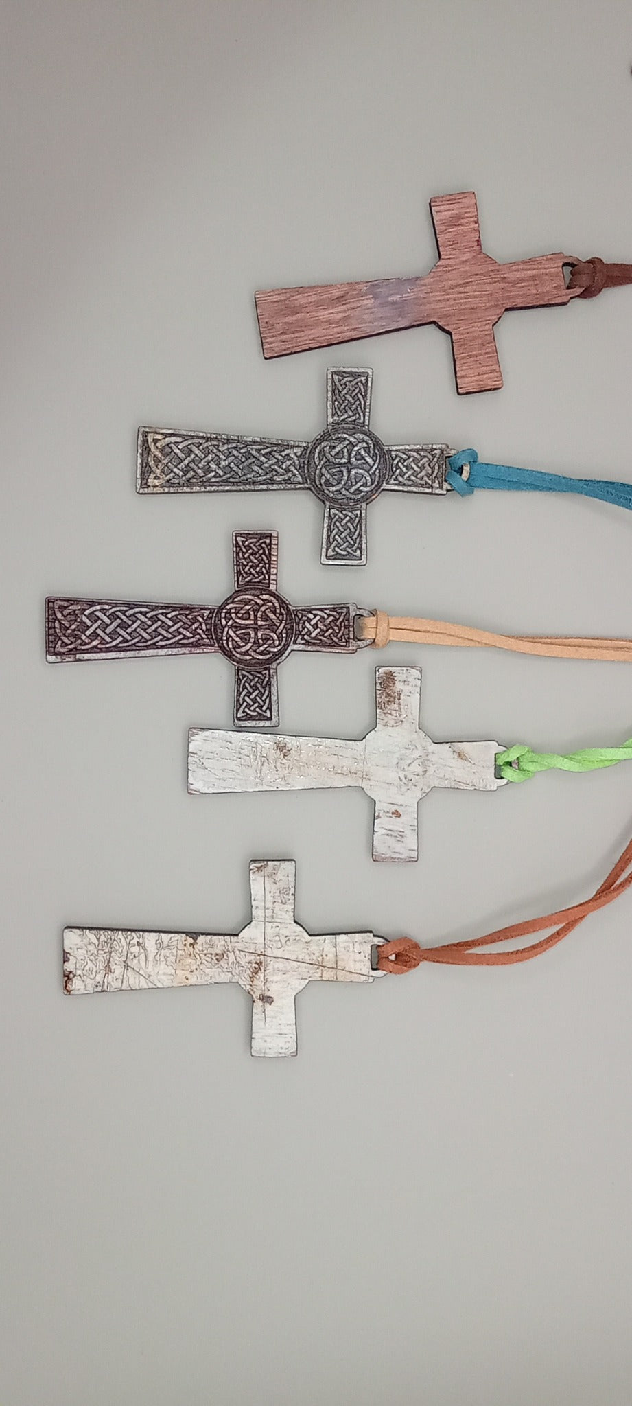 Rustic engraved wooden Celtic cross pendants showing natural workshop marks and varied finishes