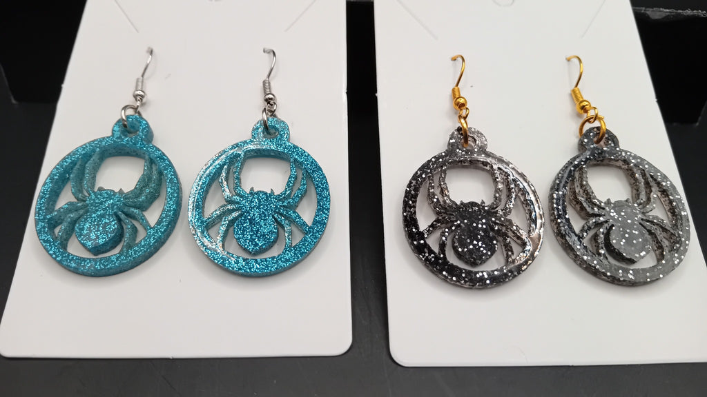 Close-up of turquoise and black sparkle spider earrings