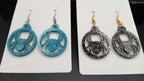 Close-up of turquoise and black sparkle spider earrings