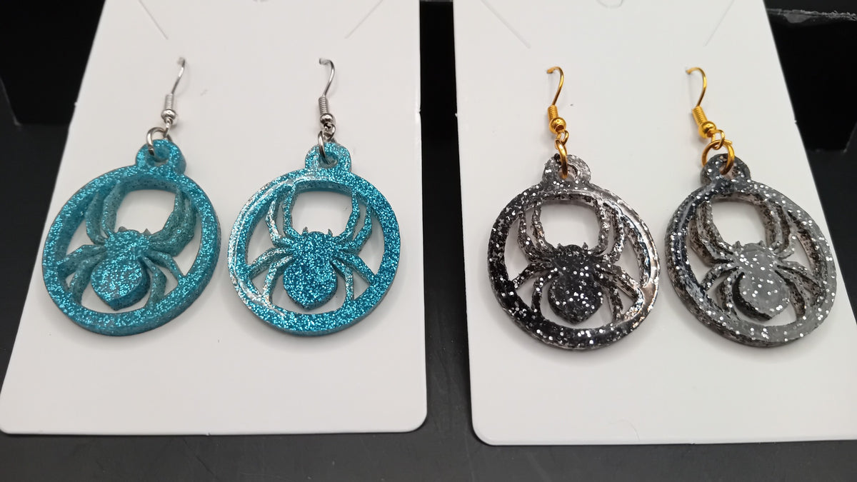 Close-up of turquoise and black sparkle spider earrings